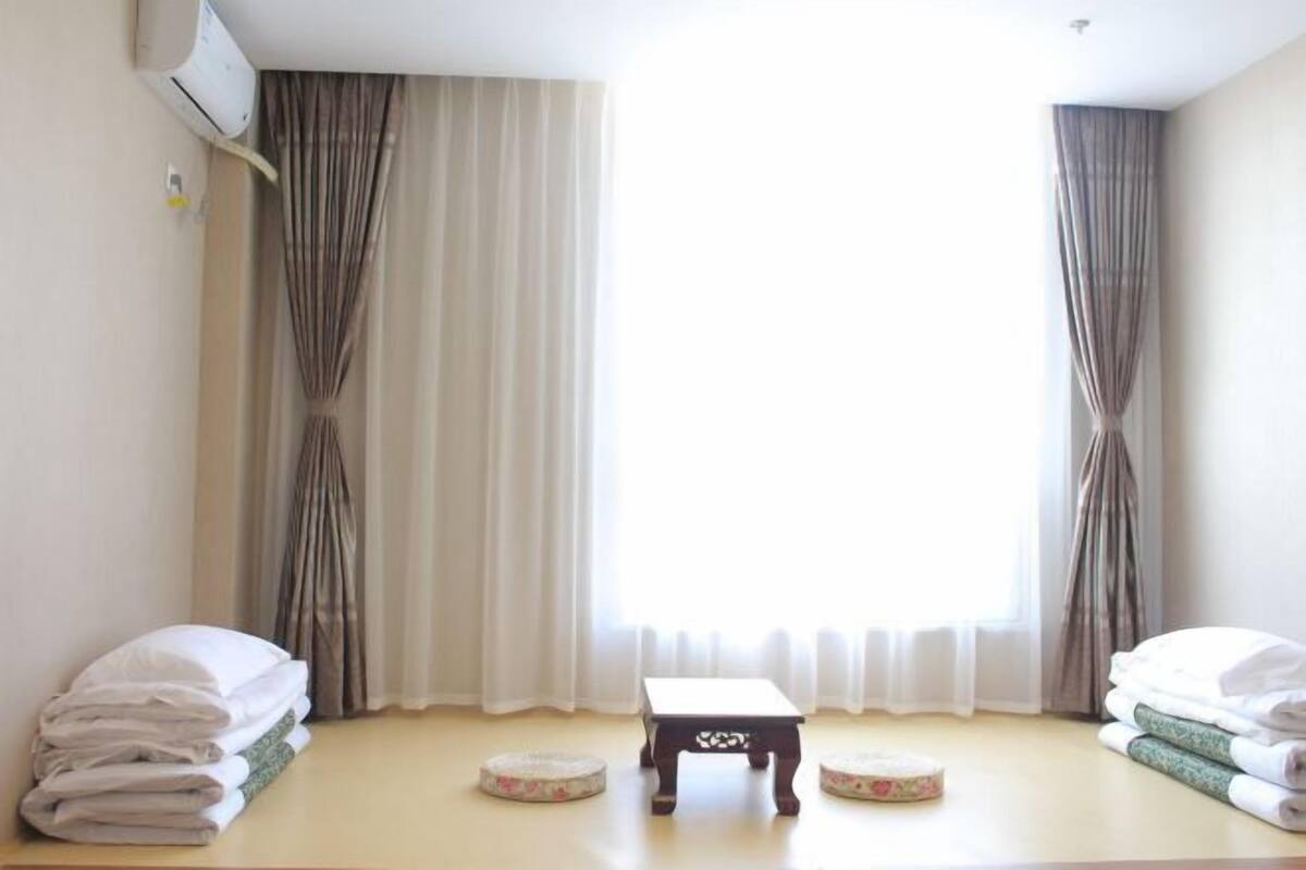 Ein Hotelzimmer mit Bett, einem kleinen Tisch und einem Fenster mit Vorhängen.