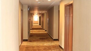 A long, narrow hotel corridor with a patterned carpet and wooden doors on both sides. - Panjin Jingang Business Hotel (Panjin)