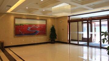 A spacious lobby with a large painting, a chandelier, and a potted plant.