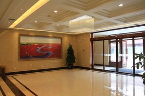 A spacious lobby with a large painting, a chandelier, and a potted plant. - Panjin Jingang Business Hotel (Panjin)