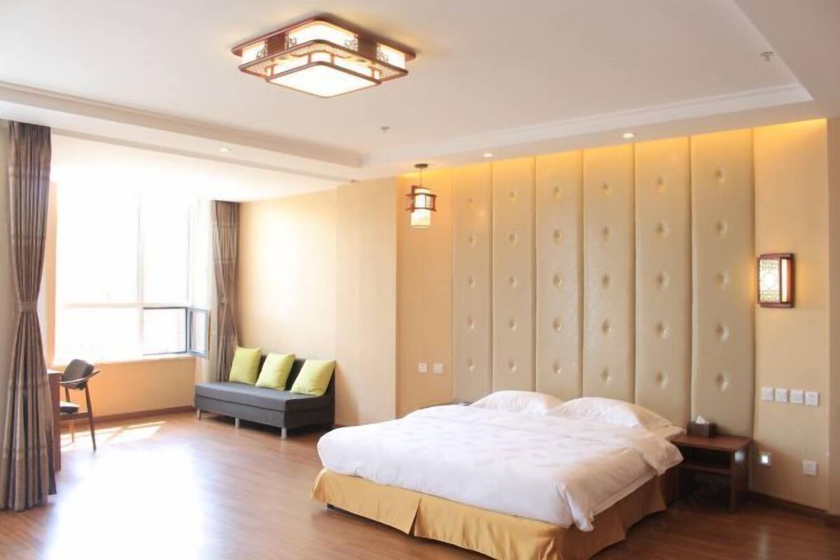 Ein Hotelzimmer mit einem großen Bett, einer Couch, einem Sessel und einem Fenster mit Vorhängen.