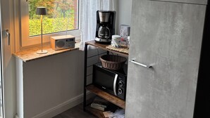 Une cuisine compacte dotée d’une fenêtre, d’une machine à café, d’un four à micro-ondes et d’un réfrigérateur.