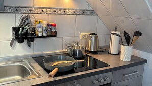 Une cuisine moderne équipée d’une cuisinière, d’un four et d’un évier. On y trouve des ustensiles de cuisine et des épices sur le plan de travail.