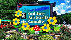 Señal para la Great Smoky Arts & Crafts Community, con flores decorativas y osos.