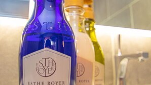 Un bagno con una bottiglia blu etichettata 'ESTHE ROYER' e una bottiglia gialla sullo sfondo.