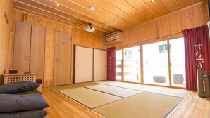 Una tradizionale stanza giapponese con pavimenti in tatami, porte scorrevoli e una ventola a soffitto.