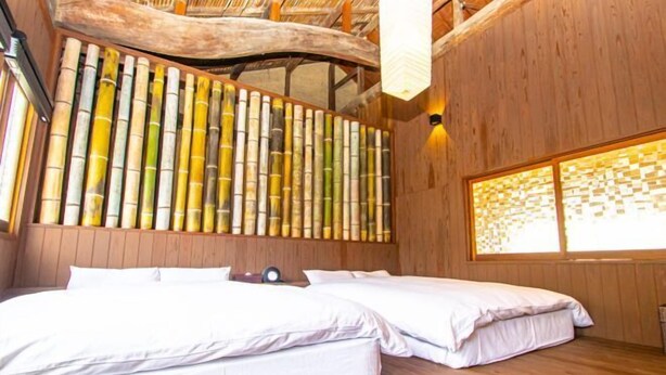 Una stanza con un letto, pareti in legno, una parete in bambù e una finestra con persiana decorata.