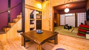 Interno in legno con una scala, un tavolo con un piatto e tradizionali tatami giapponesi.