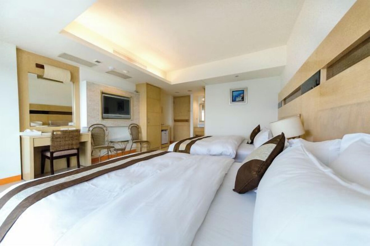 A hotel room with a large bed, a desk, and a television.