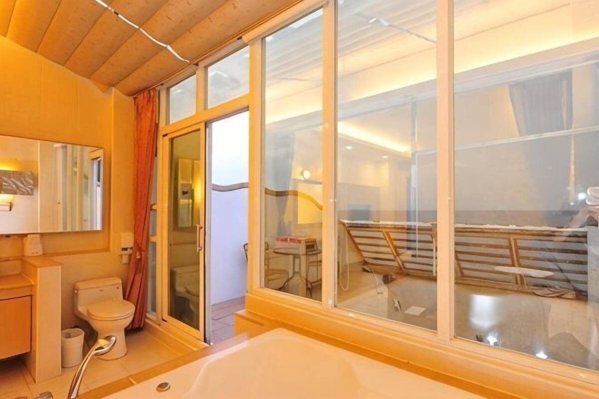 A bathroom with a bathtub, toilet, and shower, large sliding glass doors leading to a balcony.