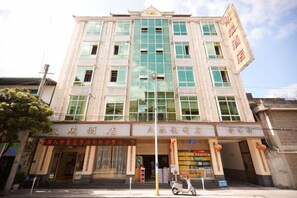 Un edificio de varios pisos con una entrada destacada, señalización y cielo despejado.