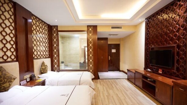 Quarto de hotel com duas camas, uma TV e uma parede de destaque em madeira.