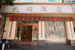 A hotel entrance with a signboard and a glass door.