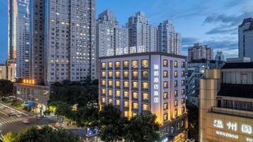 A multi-story hotel with a modern facade, located in an urban setting with high-rise buildings in the background.