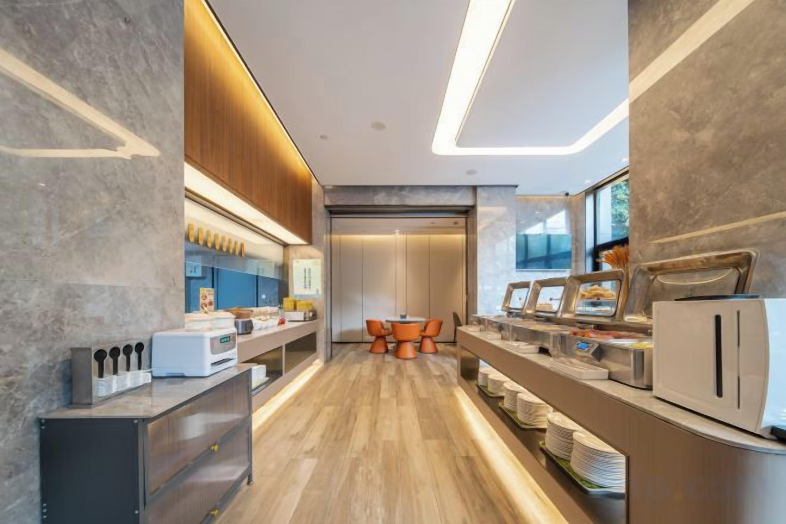 A modern kitchen with a wooden floor, built-in appliances, and a dining area with orange chairs.