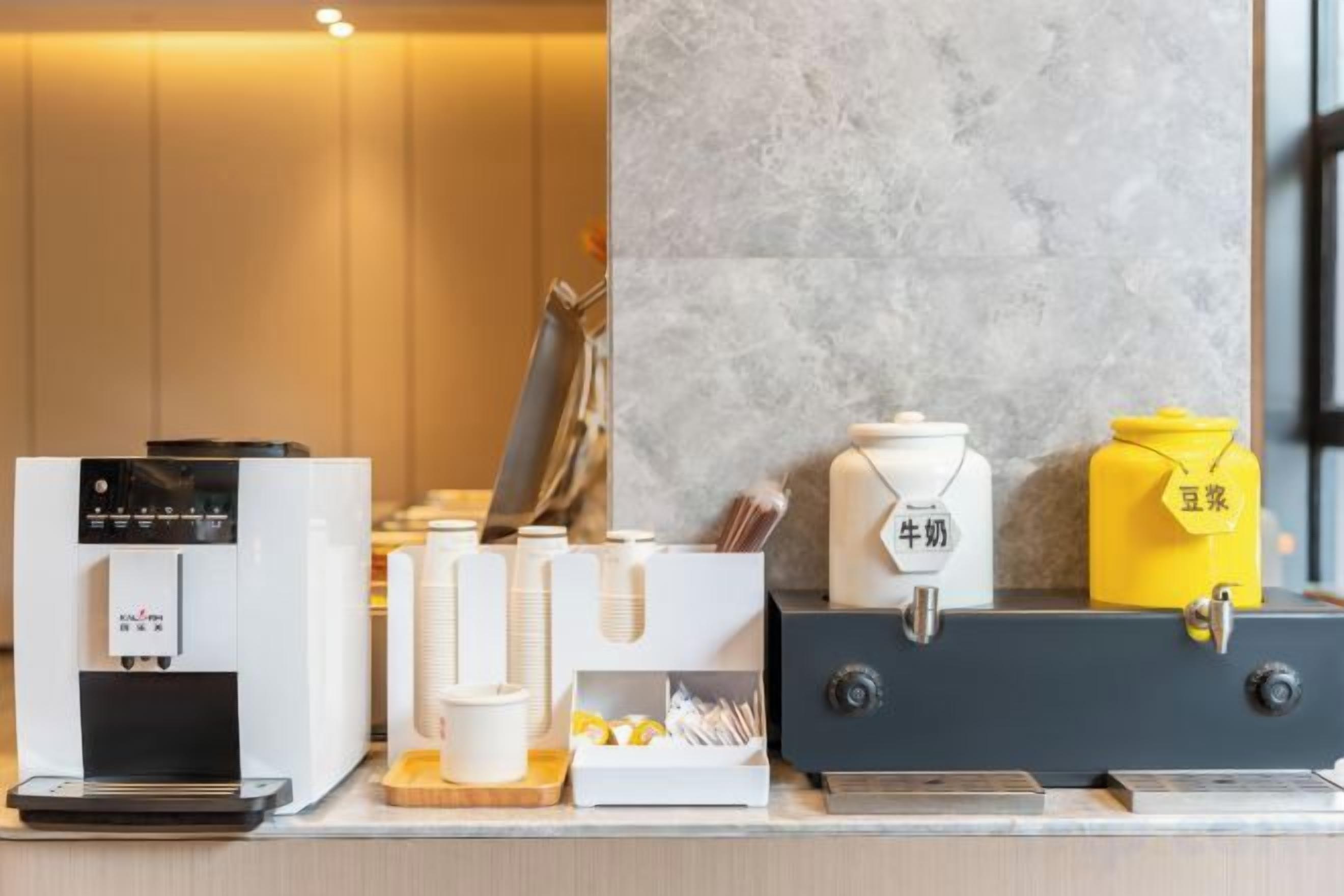 Una estación de café con cafetera, espumador de leche y recipientes.