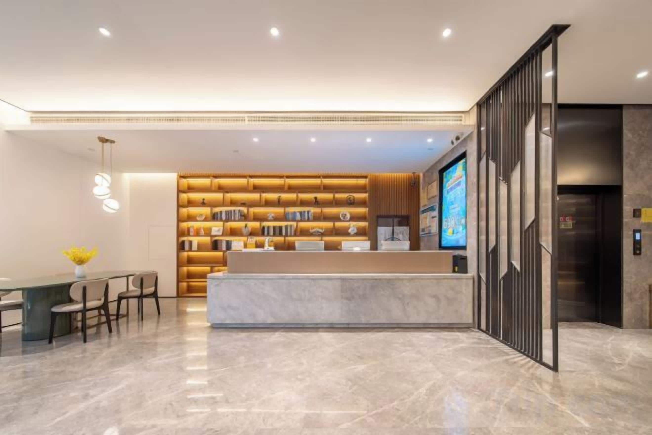 A hotel lobby with a reception desk, a seating area, and a wall of bookshelves.