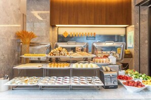 Un bufé con diferentes opciones de comida y una estación de café.