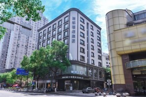 A multi-story hotel with a classic architectural design, featuring a prominent entrance and a large tree in front. - Ruidu E Hotel (Wenzhou Wuma Street) (Wenzhou)