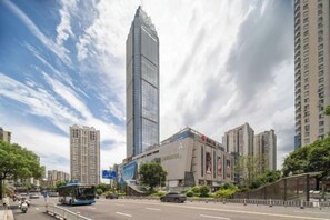 A city street with high-rise buildings, a bus, and a pedestrian walkway.