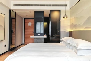 Een moderne hotelkamer met een groot bed, een klein bureau en uitzicht op een berglandschap.