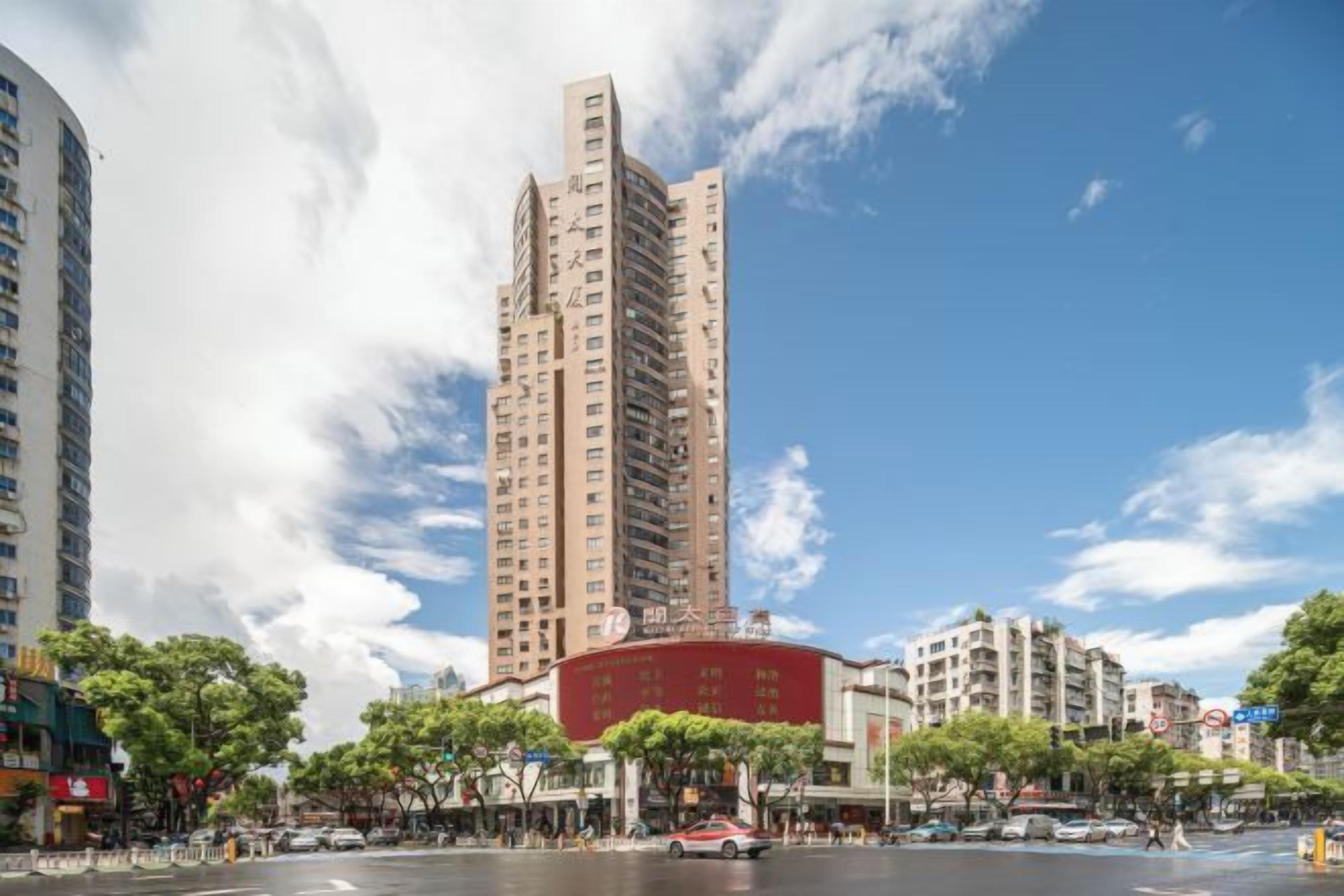 A high-rise building with a modern design, surrounded by other buildings and trees.