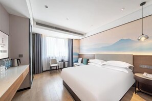 A modern hotel room with a large bed, a desk with a chair, a small table, and a wall-mounted phone. - Ruidu E Hotel (Wenzhou Wuma Street) (Wenzhou)