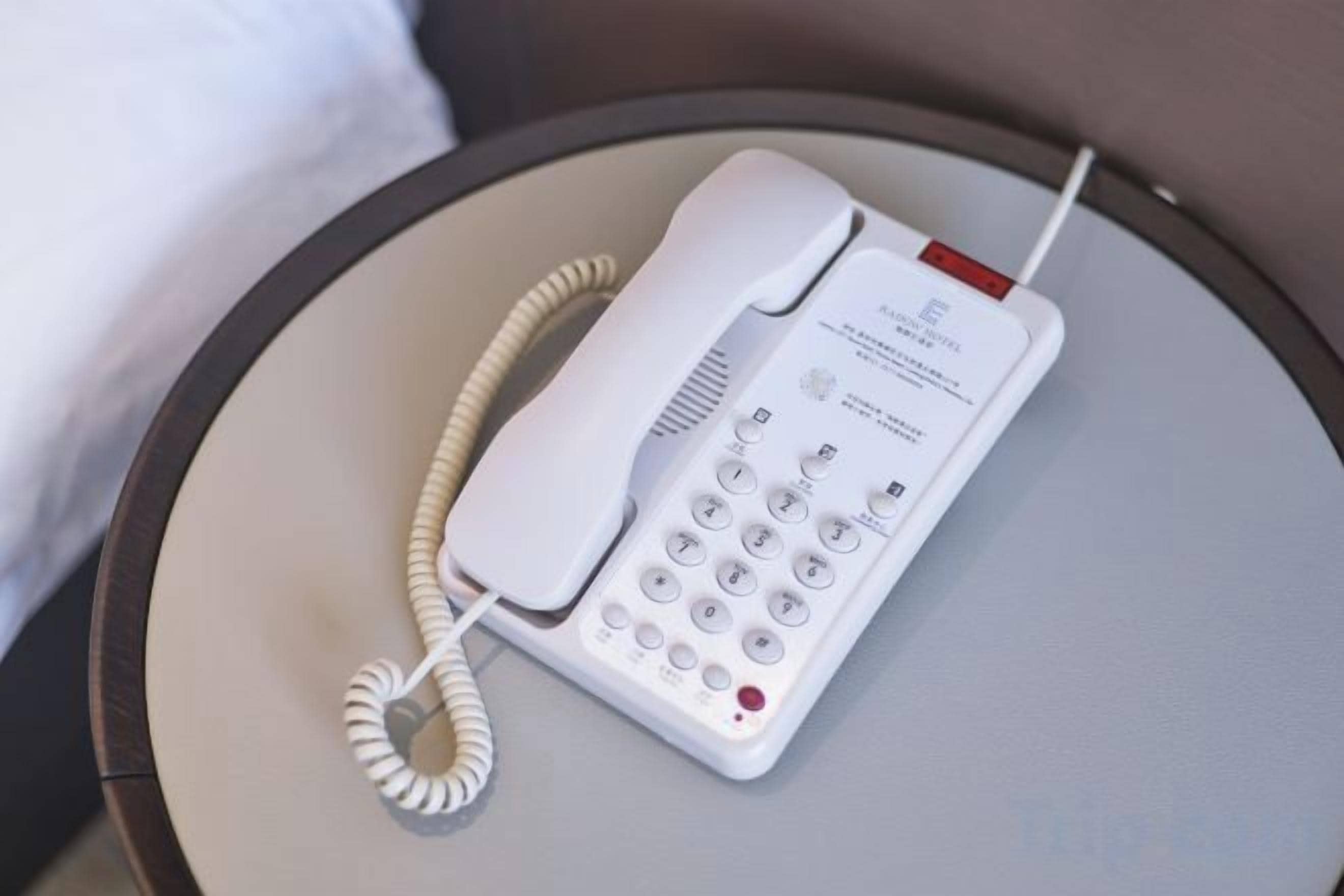A white hotel phone on a round table.