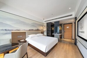 A modern hotel room with a large bed, a desk, and a view of a mountainous landscape. - Ruidu E Hotel (Wenzhou Wuma Street) (Wenzhou)