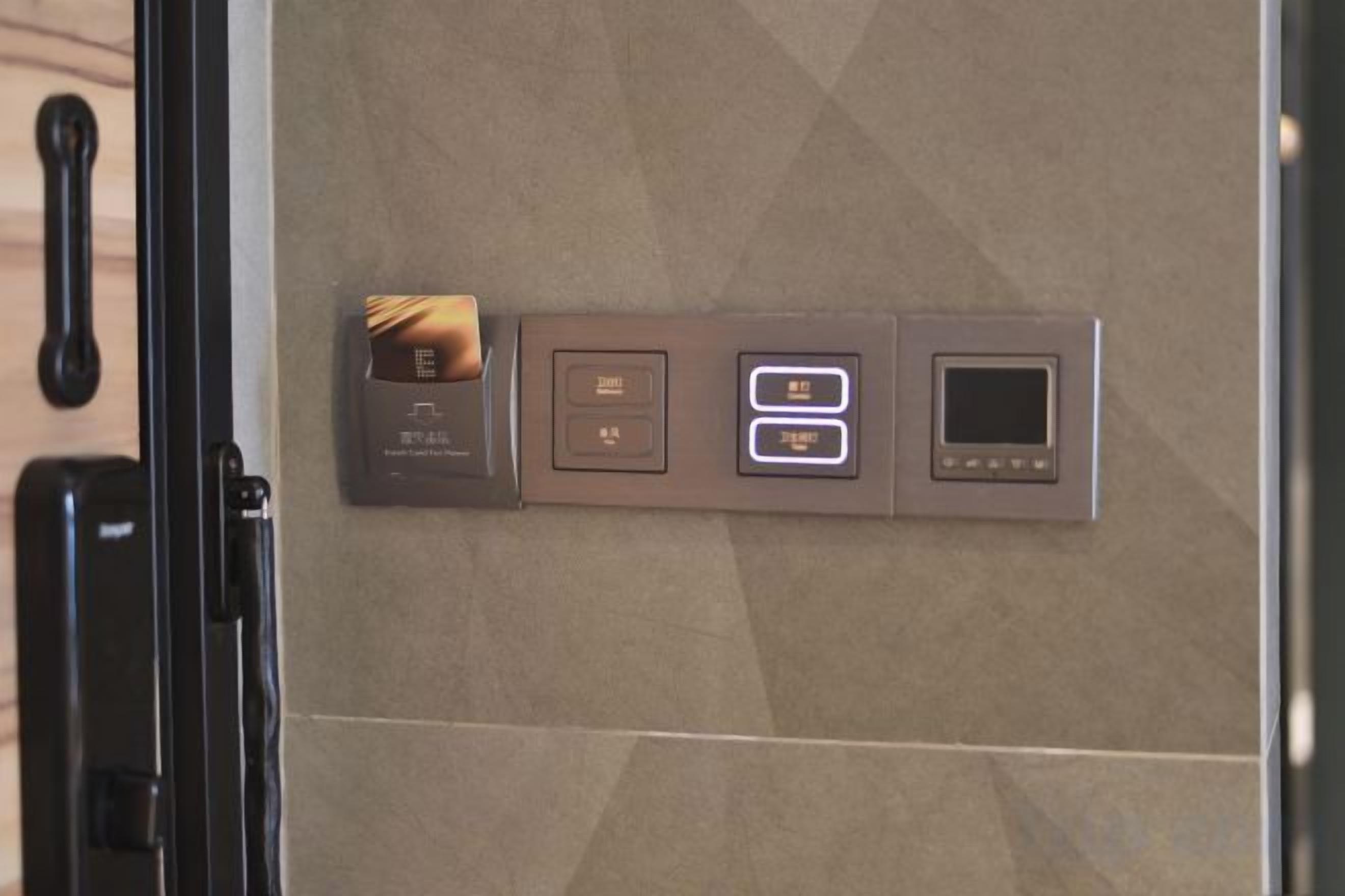 Painel de controle com leitor de cartão, duas teclas iluminadas e uma tela pequena.