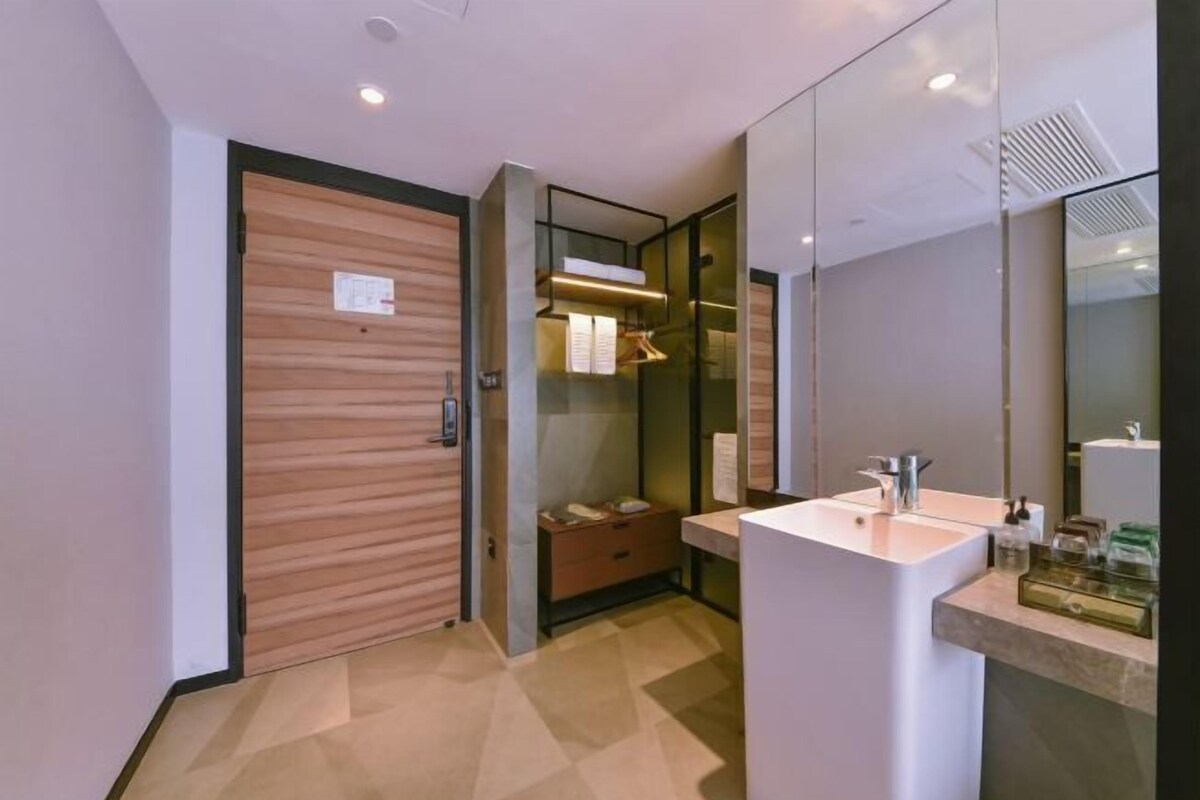 A modern bathroom with a wooden door, a glass shower enclosure, and a white sink with a mirror.
