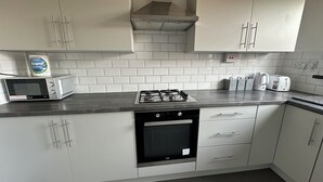 A modern kitchen with white cabinets, a gas stove, a microwave, and a dishwasher.