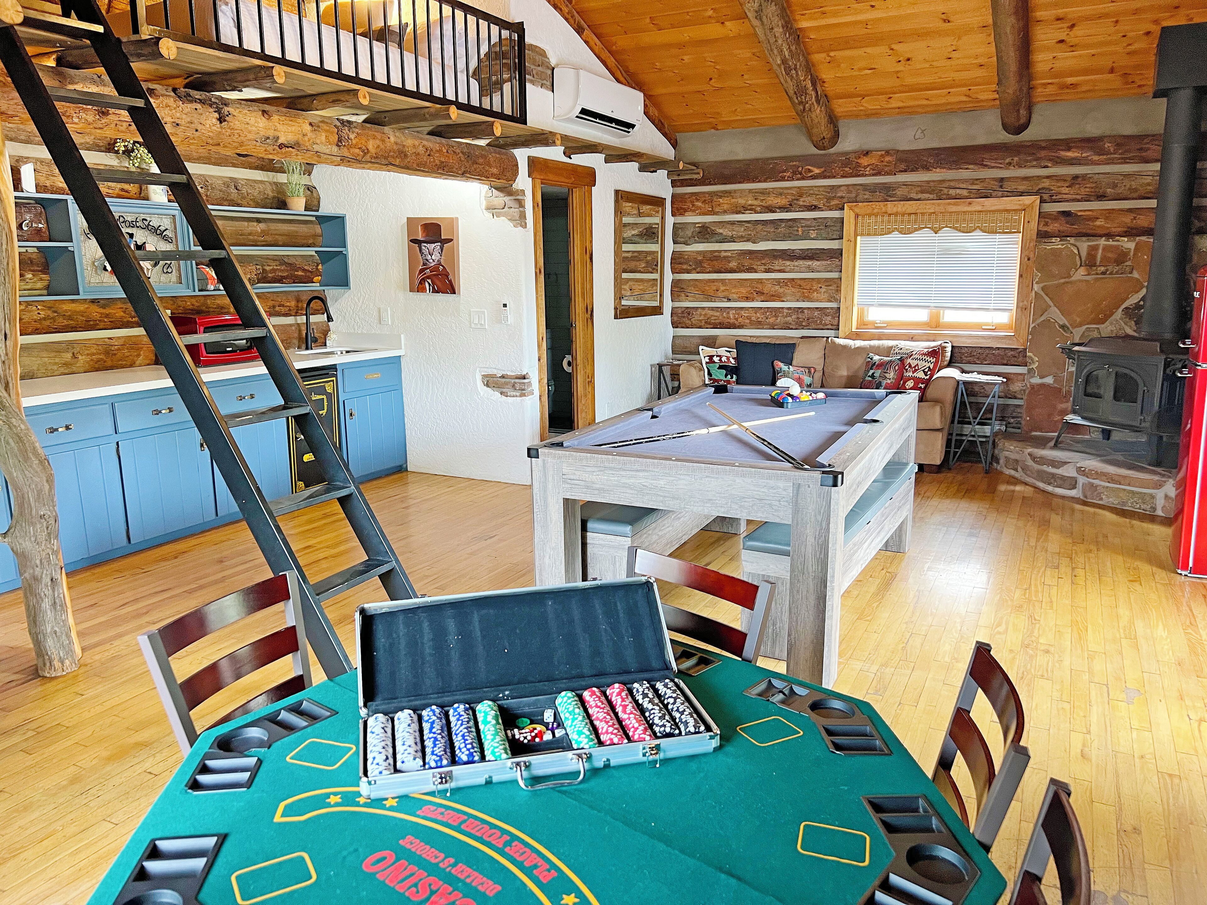 A cozy room with a pool table, a wooden staircase, and a stone fireplace.