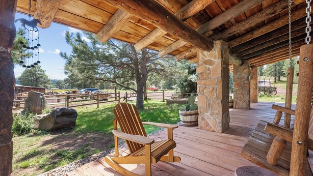 A wooden rocking chair on a wooden deck with a stone wall and wooden beams overhead. - Renovated Historic Flagstaff Cabin, Trails, Hot tub  (Flagstaff)