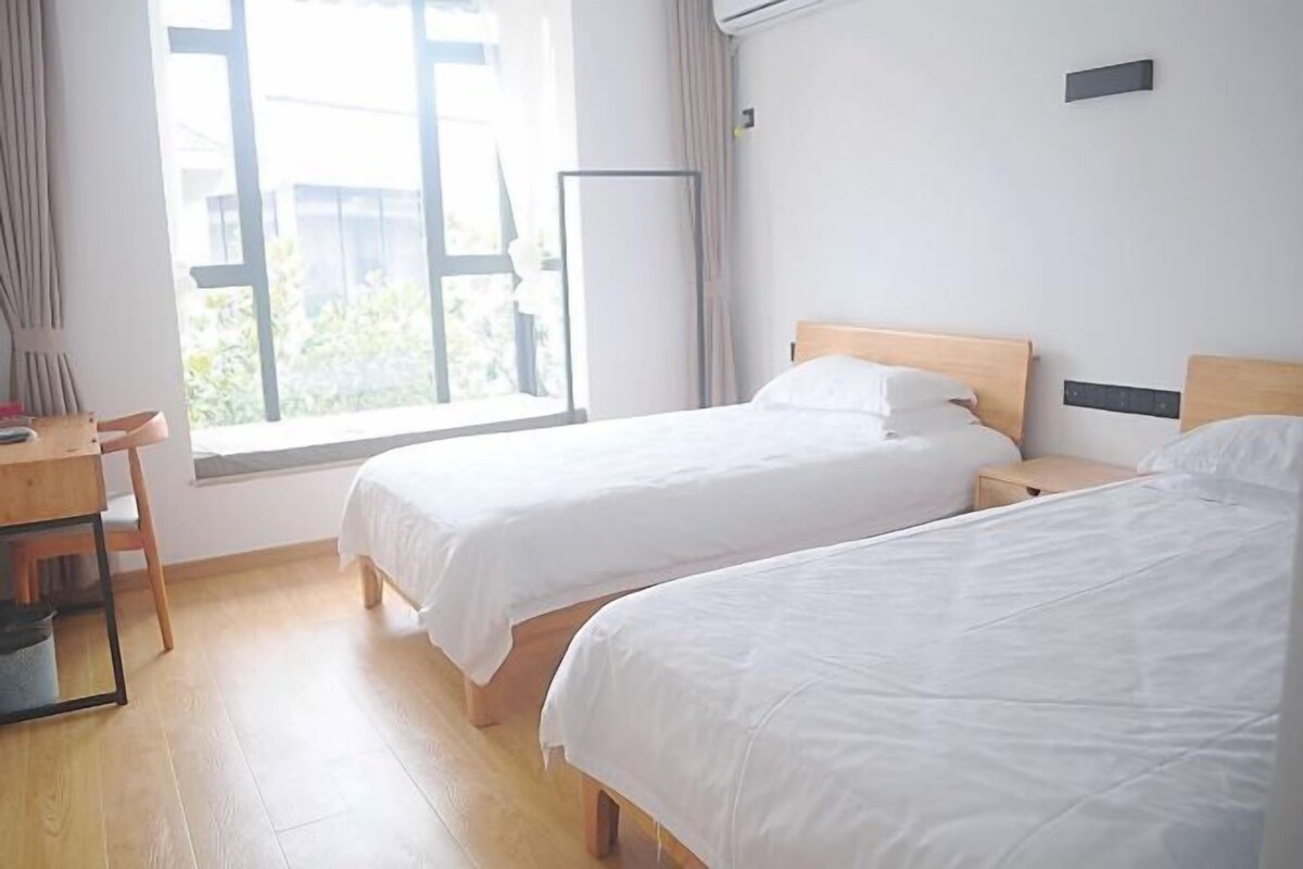 Habitación de hotel con dos camas, un escritorio y una ventana con cortinas.