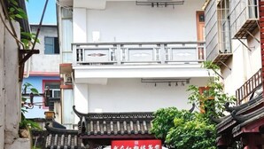 A traditional building with a red sign, a balcony, and a tiled roof.