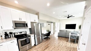 A modern kitchen with stainless steel appliances, white cabinets, and a wooden floor.