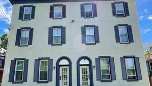 A two-story building with a symmetrical facade, featuring a central entrance with double doors and a small porch.