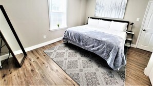 A bedroom with a bed, a window, a painting, and a door.