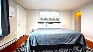 Un dormitorio con cama, dos mesitas de noche, una ventana y una puerta.