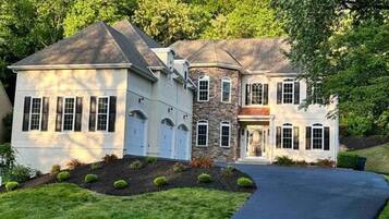 A two-story house with a stone facade, a driveway, and a well-maintained lawn.