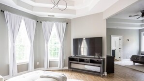 Ein modernes Wohnzimmer mit einem großen Flachbildfernseher, einer Couch und einem Essbereich mit Tisch und Stühlen.