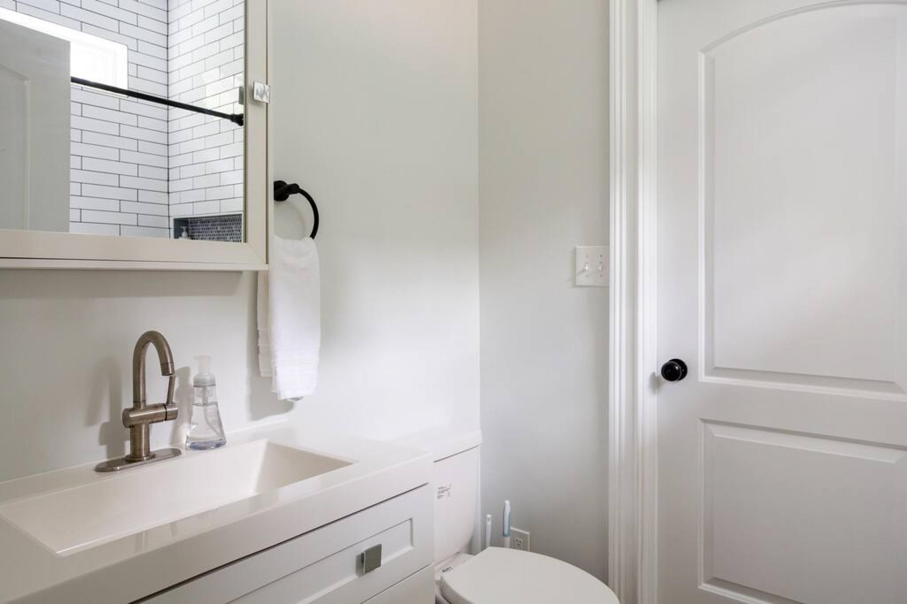 A bathroom with a white sink, a mirror, a towel rack, and a toilet.