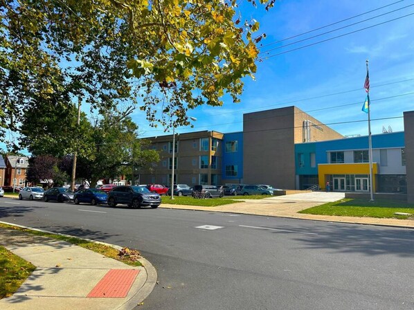 A modern building with a flat roof, large windows, and a flagpole with an American flag. - Cozy Walk up King Bed Fast Wifi (Wilmington)