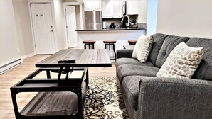 A modern living room with a gray sofa, a wooden coffee table, and a patterned rug. - Boardwalk- Large Modern Unit With King bed Fast Wifi Free Coffee and Easy Parking (Wilmington)