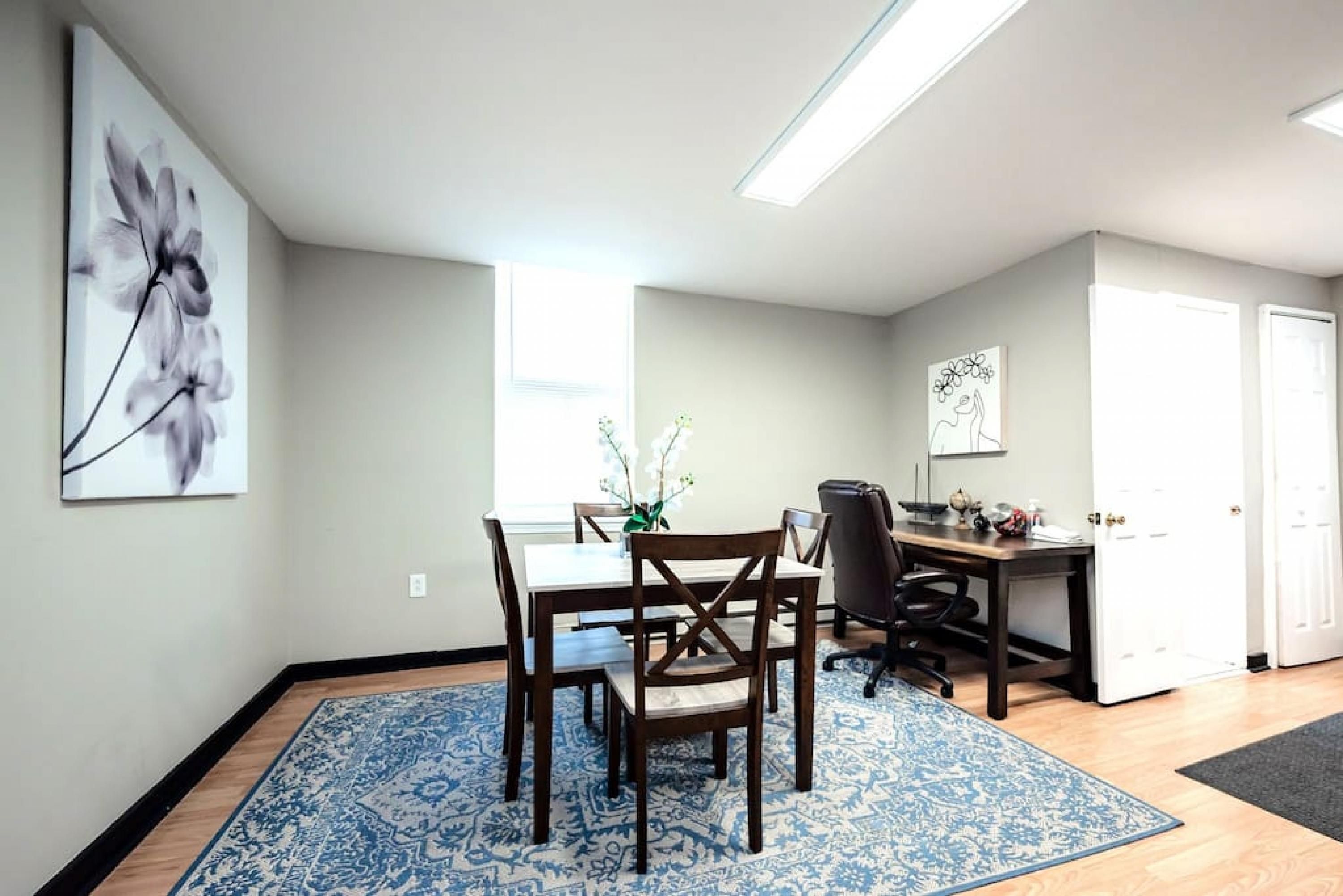 A dining area with a table, chairs, and a blue patterned rug.