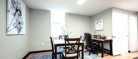 A dining area with a table, chairs, and a blue patterned rug.