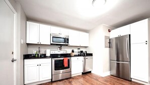 A modern kitchen with white cabinets, stainless steel appliances, and a wooden floor. - Park Place- Cozy Modern Space Fully Updated Fast Wifi Good Coffee and Easy Parking (Wilmington)