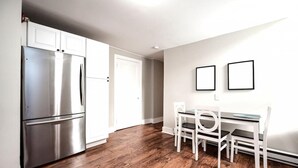 A modern kitchen with stainless steel appliances, a dining area with white furniture, and a wooden floor. - Park Place- Cozy Modern Space Fully Updated Fast Wifi Good Coffee and Easy Parking (Wilmington)