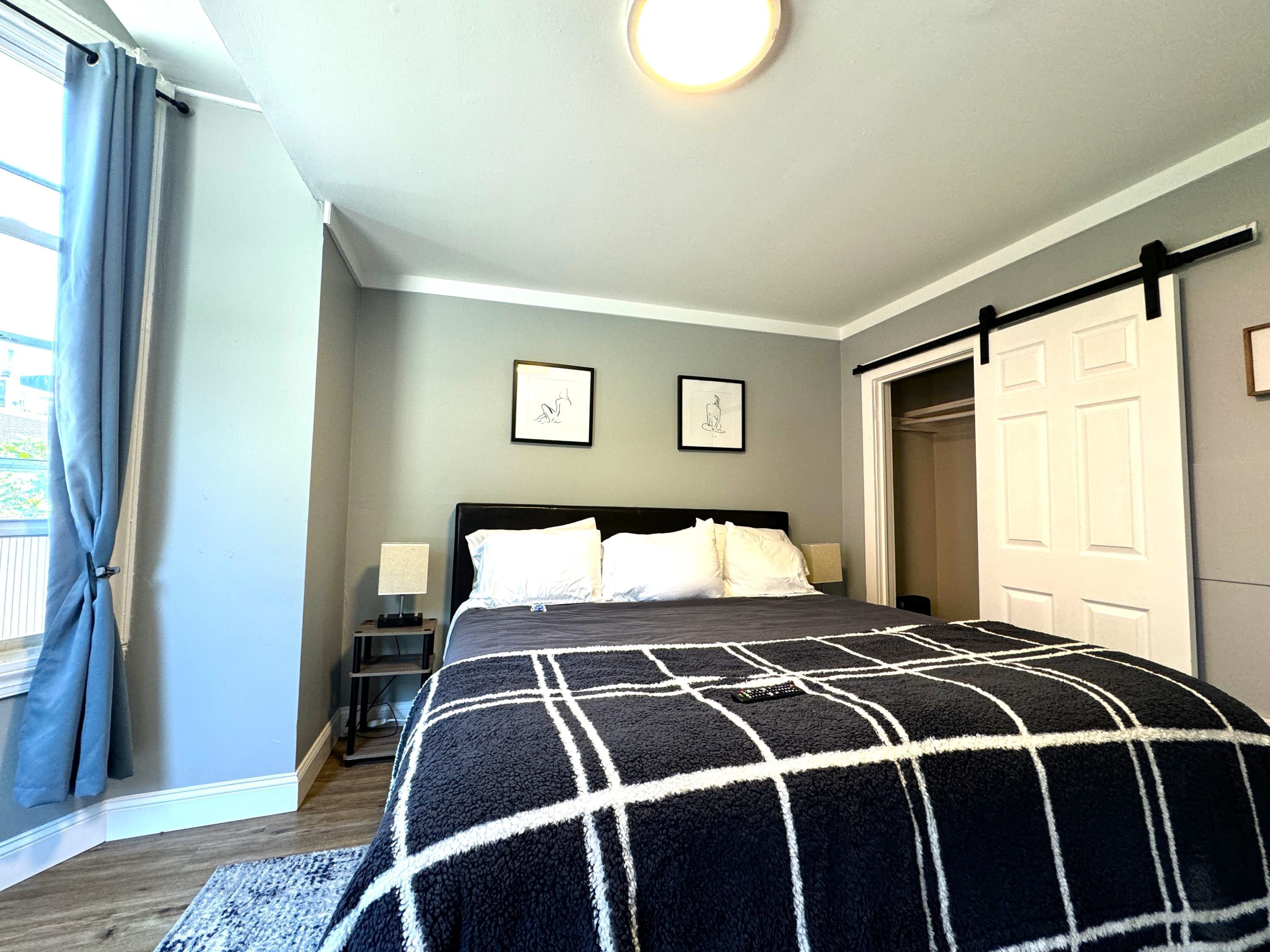 A bedroom with a bed, a nightstand, a lamp, a framed picture on the wall, and a sliding door.